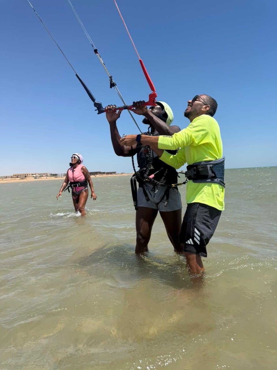 Instructor helping a student hold the control bar overhead in shallow water