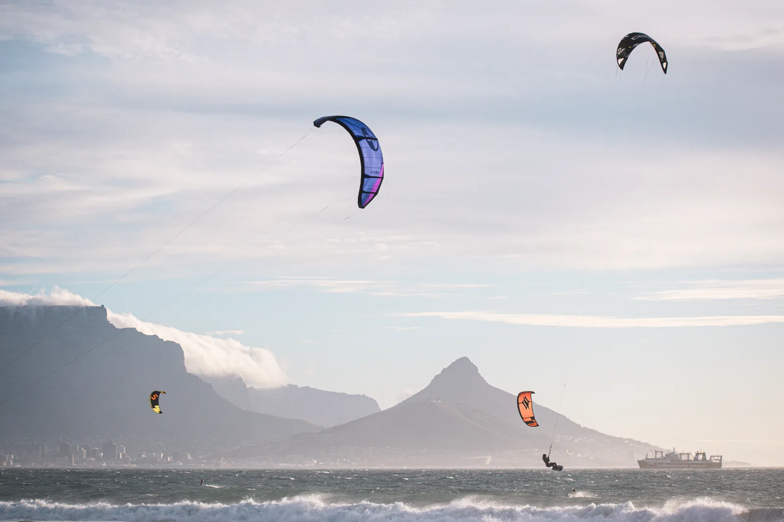 Kitesurfers riding in strong Cape Town wind beneath Table Mountain