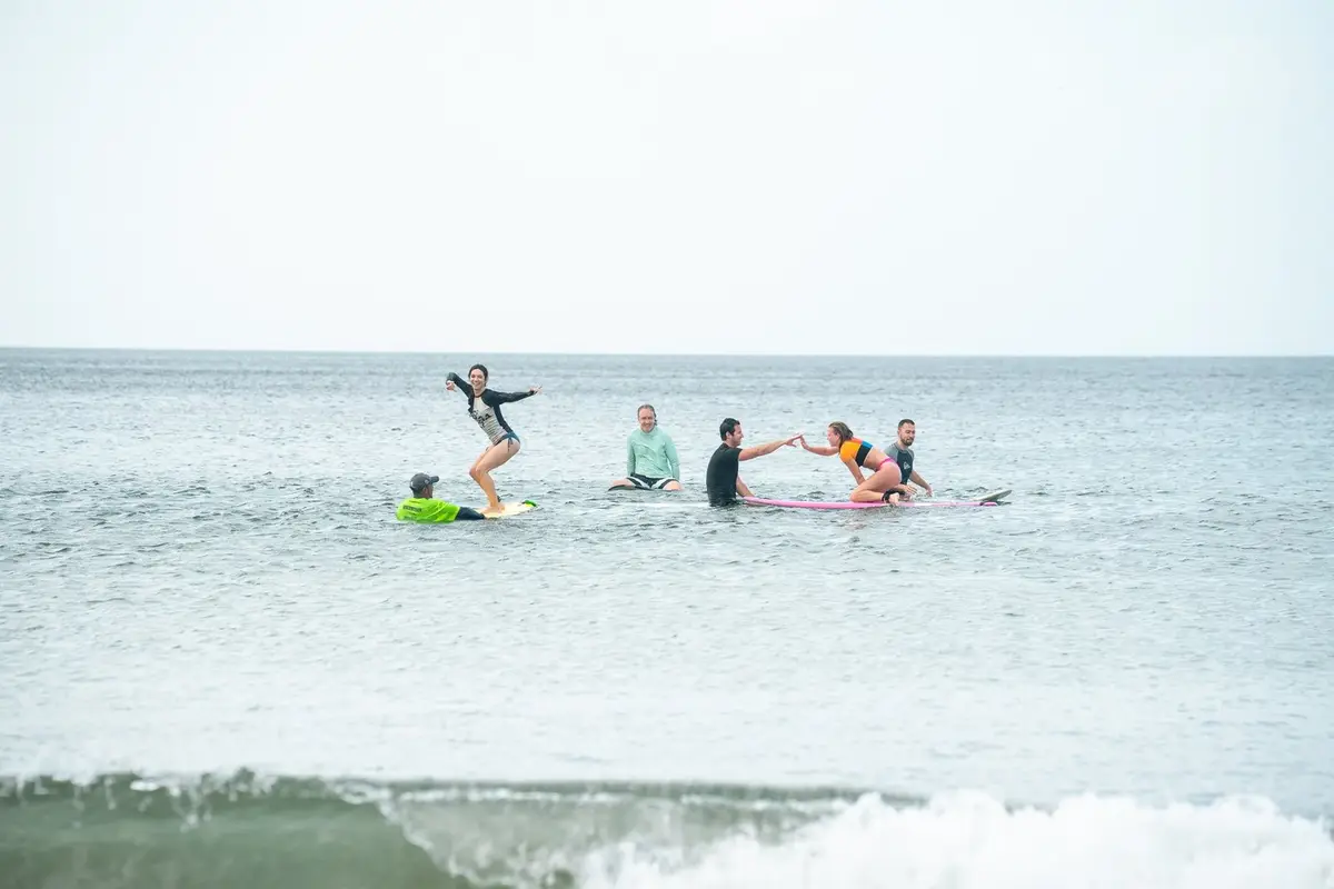 Students and coaches on surfboards in the water during a lesson at Playa Maderas
