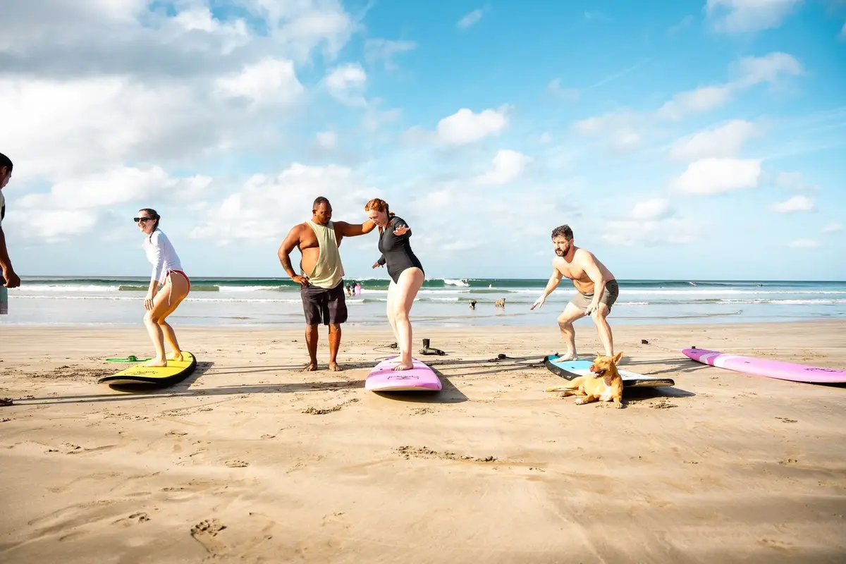 Students practising the surf stance on boards on the sand at Playa Maderas while a Beach Break coach guides them
