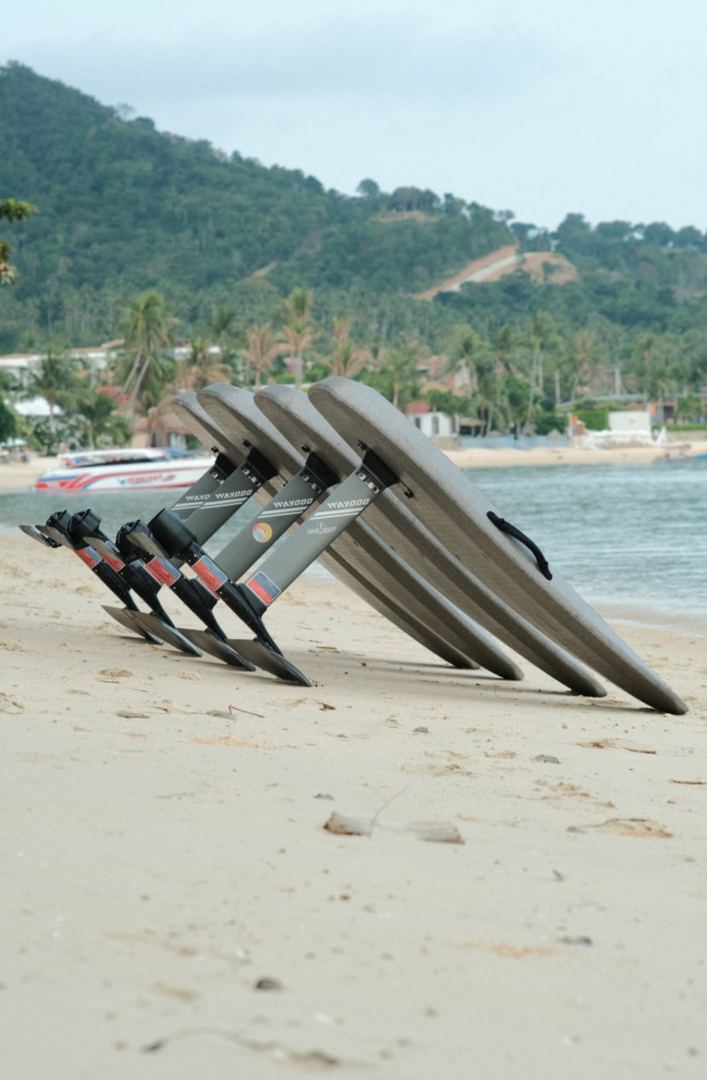E-foil boards lined up on the beach below the green hills