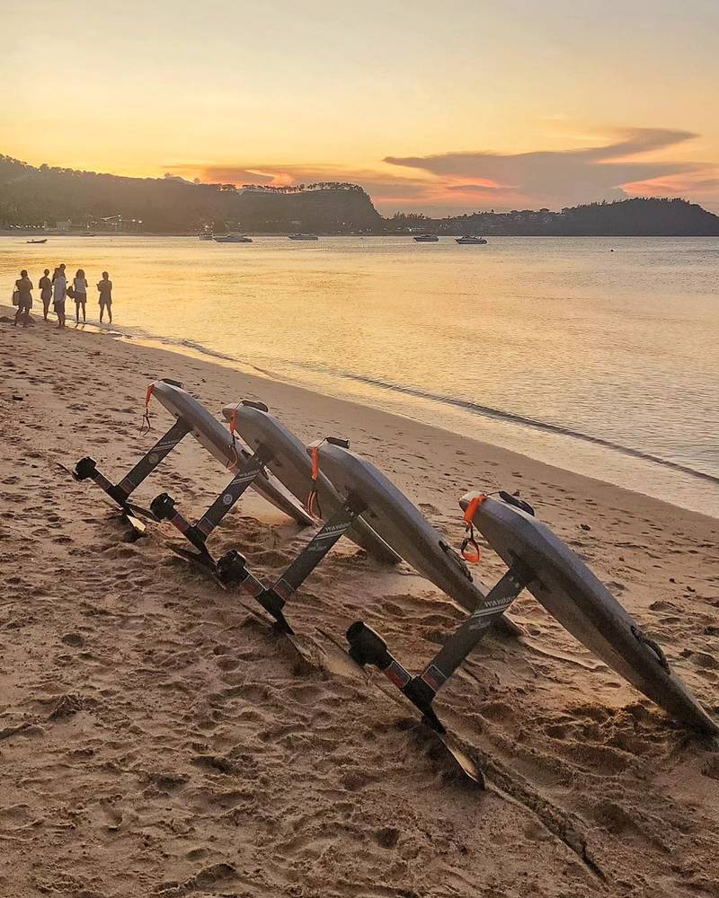 E-foil boards lined up on the sand at sunset