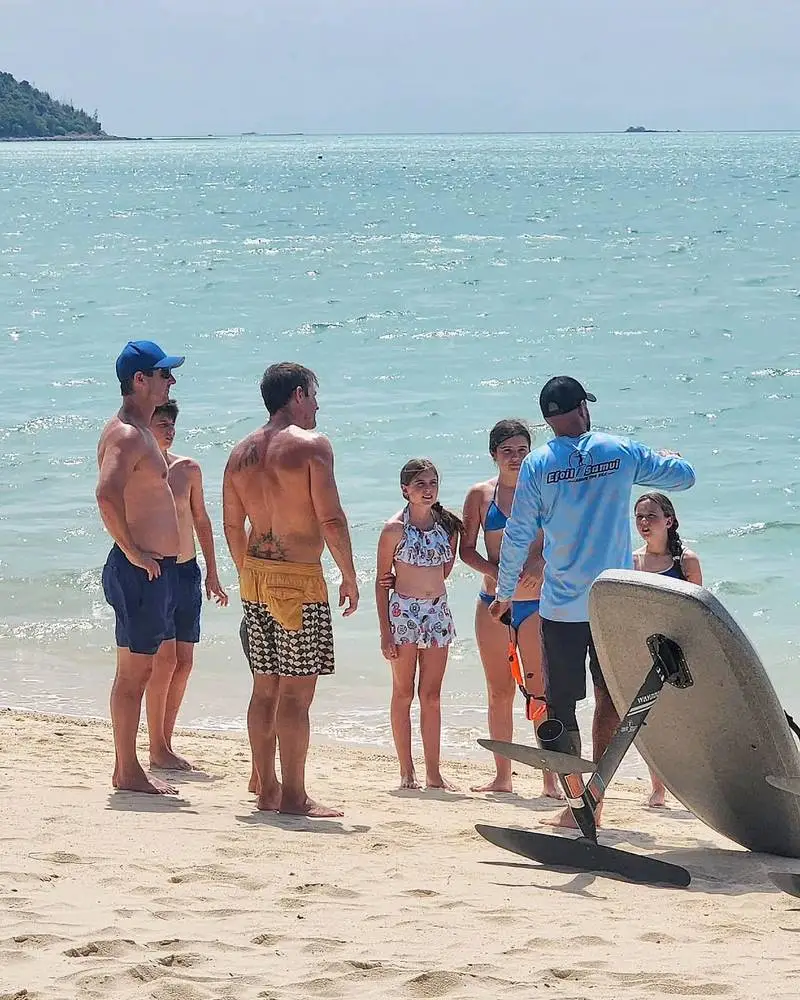An instructor briefing a family with kids on the beach before their e-foil session