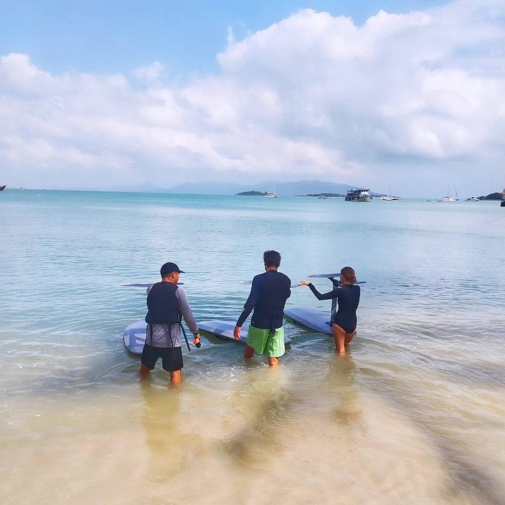Instructor briefing guests in knee-deep water next to a board