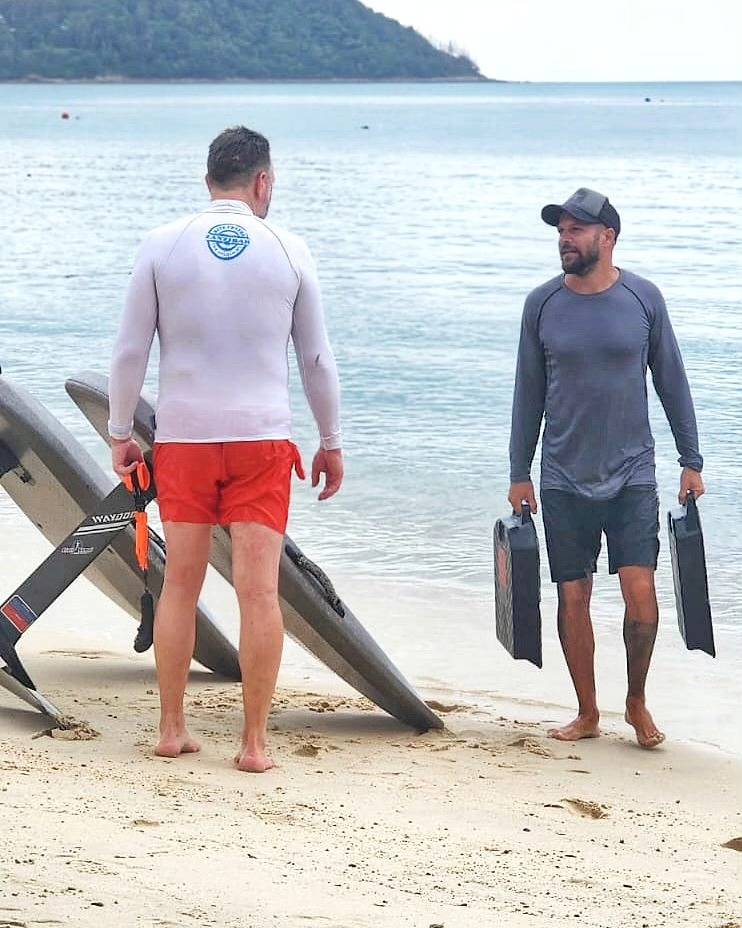 Two instructors carrying the boards and batteries to the water