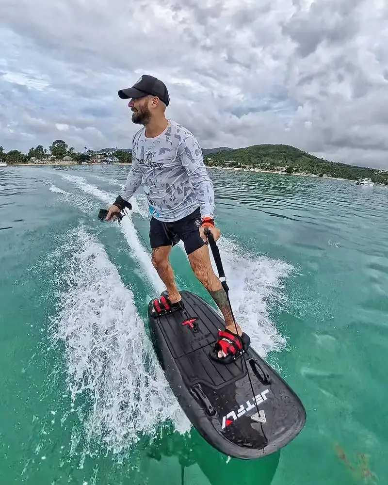 A jetsurf rider carving with spray across the water