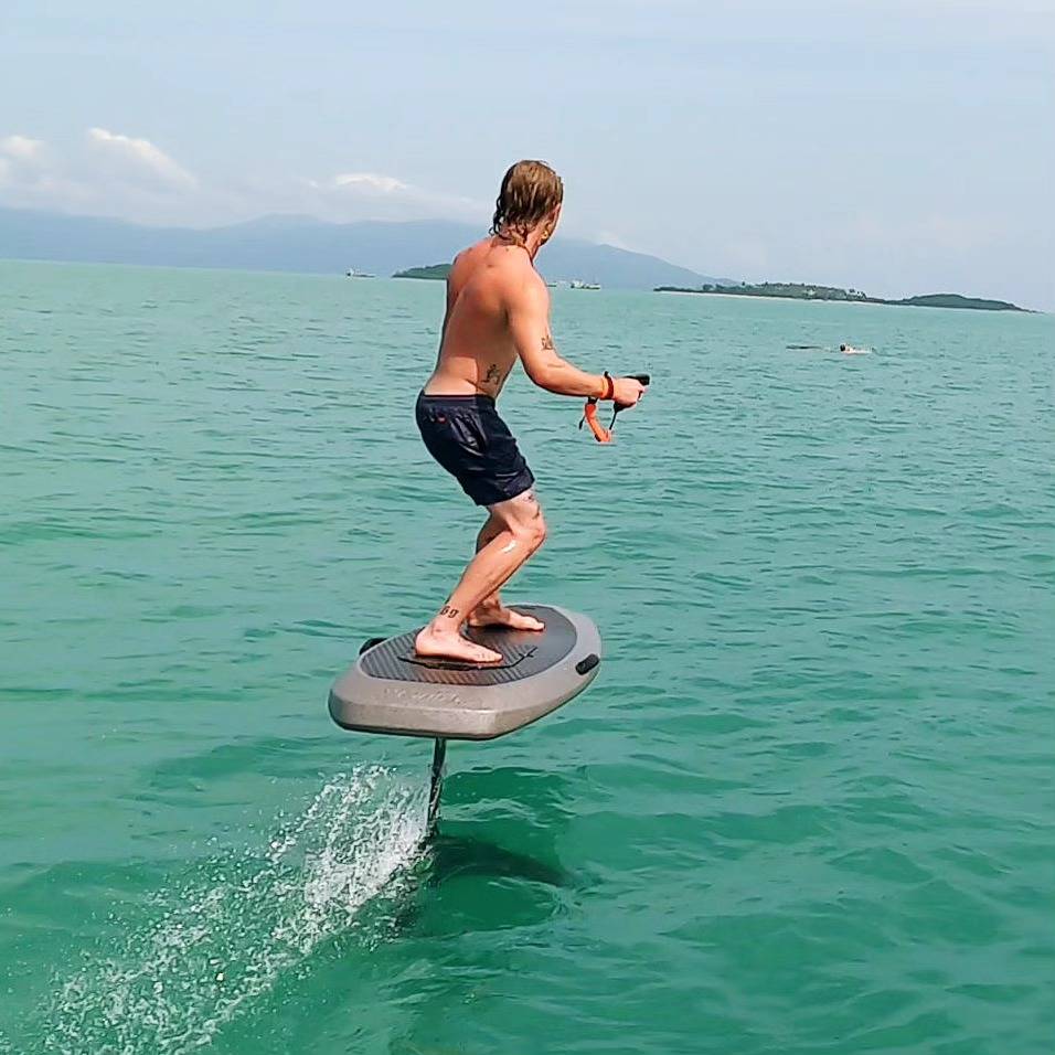 Rider lifting off on the e-foil with spray behind the board