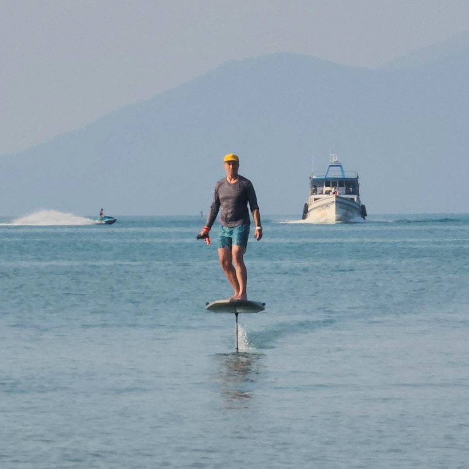 Rider on the e-foil passing a speedboat