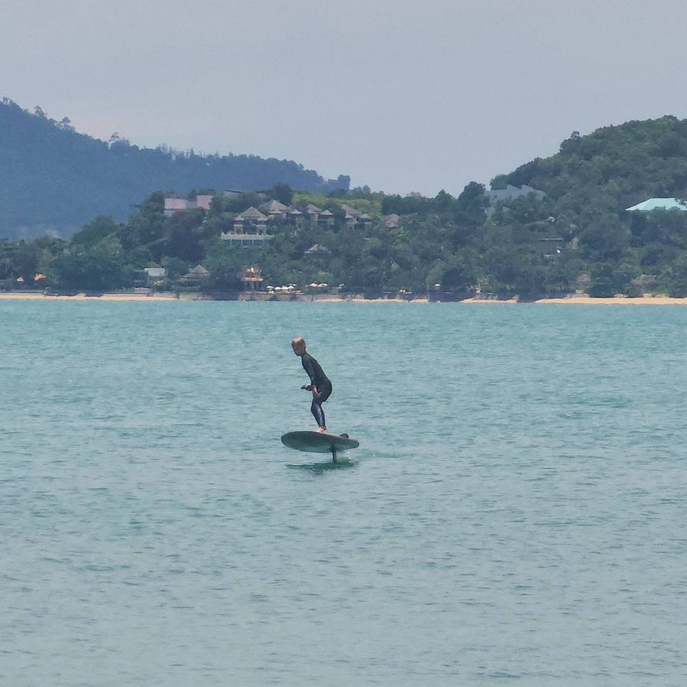 E-foil rider far out in the bay below green hills