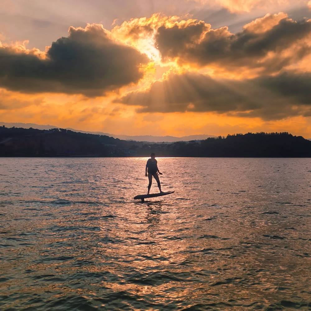 Rider silhouetted against an orange sunset over the bay