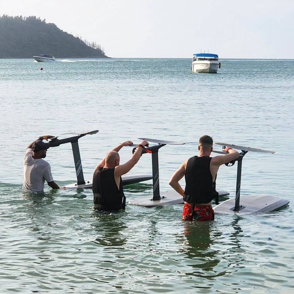 Three e-foil boards held ready in the shallow water