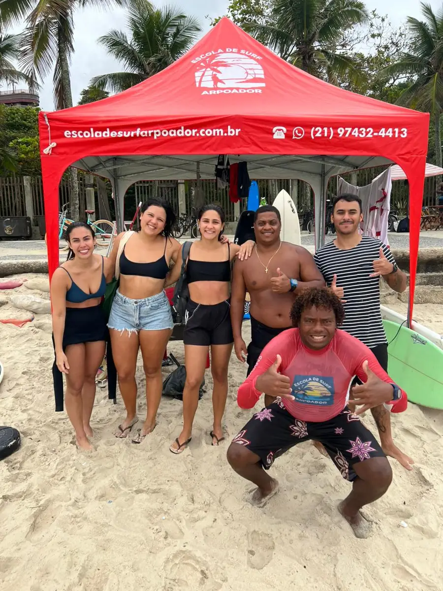 Instructors and students smiling in front of the school's red tent on the beach