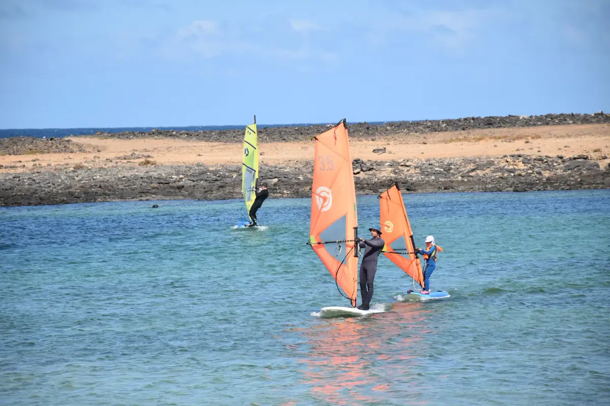 Two windsurf students practising on the calm turquoise water of Playa del Río