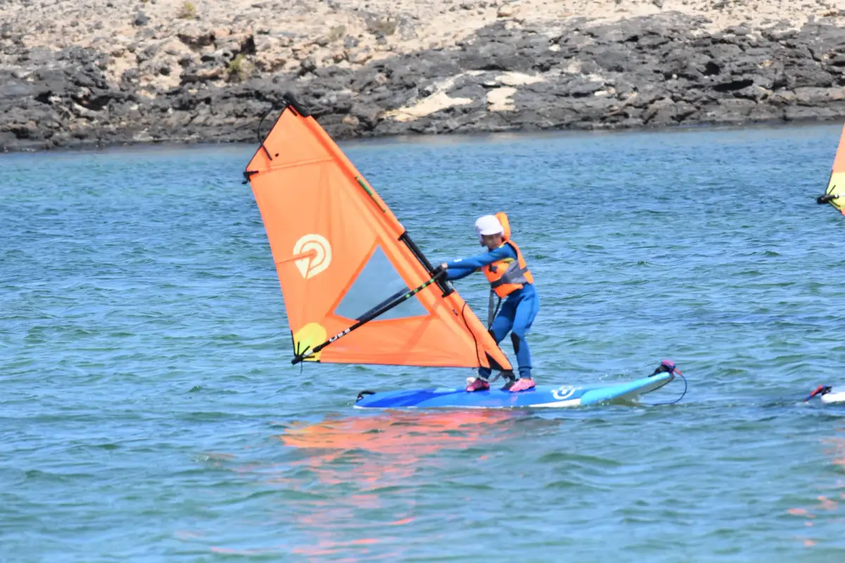 A student learning sail control on a small orange rig at Playa del Río