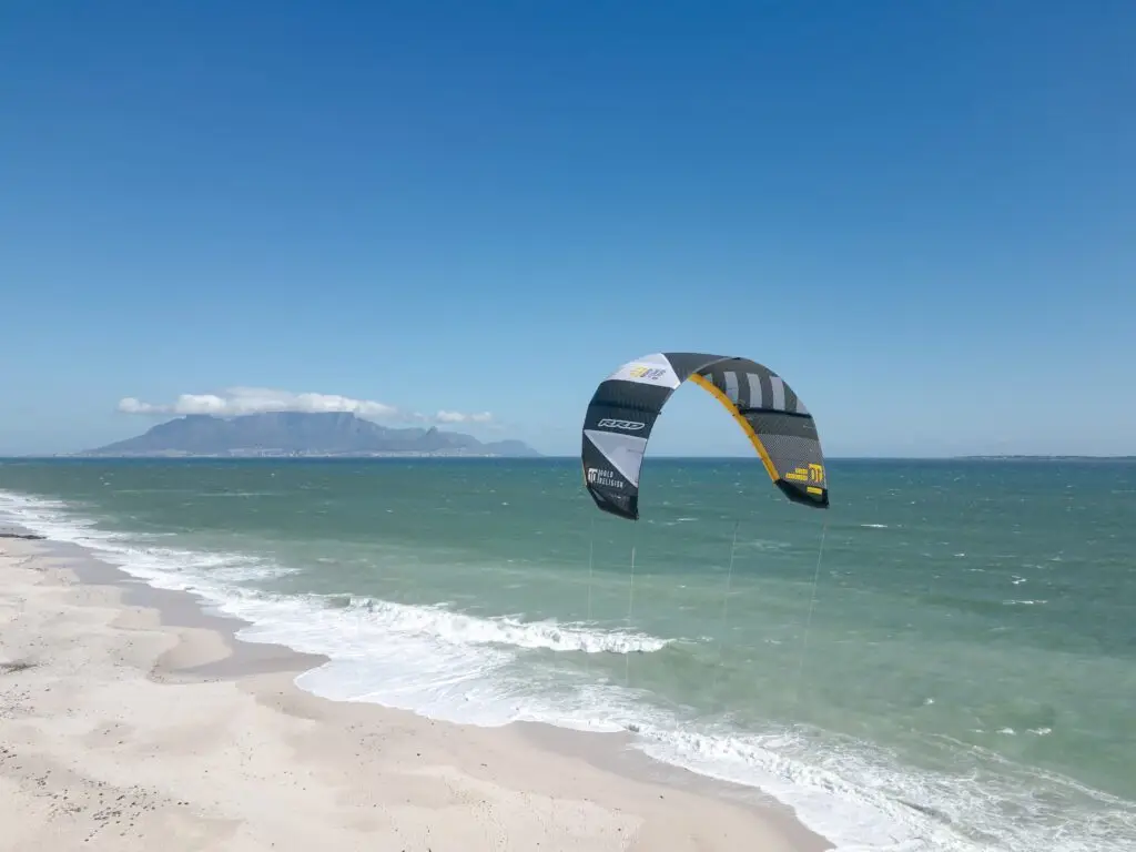 A kite flying over the bay with Table Mountain in the distance, seen from the beach