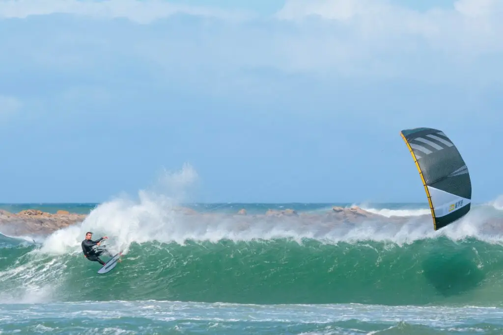 A kitesurfer turning on a wave with a green kite above