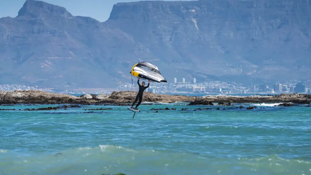 A wing foiler riding the water in front of the mountains of the Cape