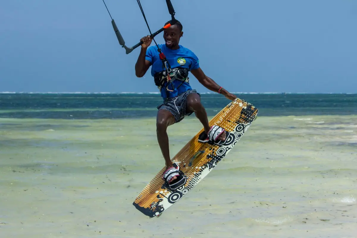Kitesurfer jumping with an orange board in warm turquoise water off Watamu, Kenya