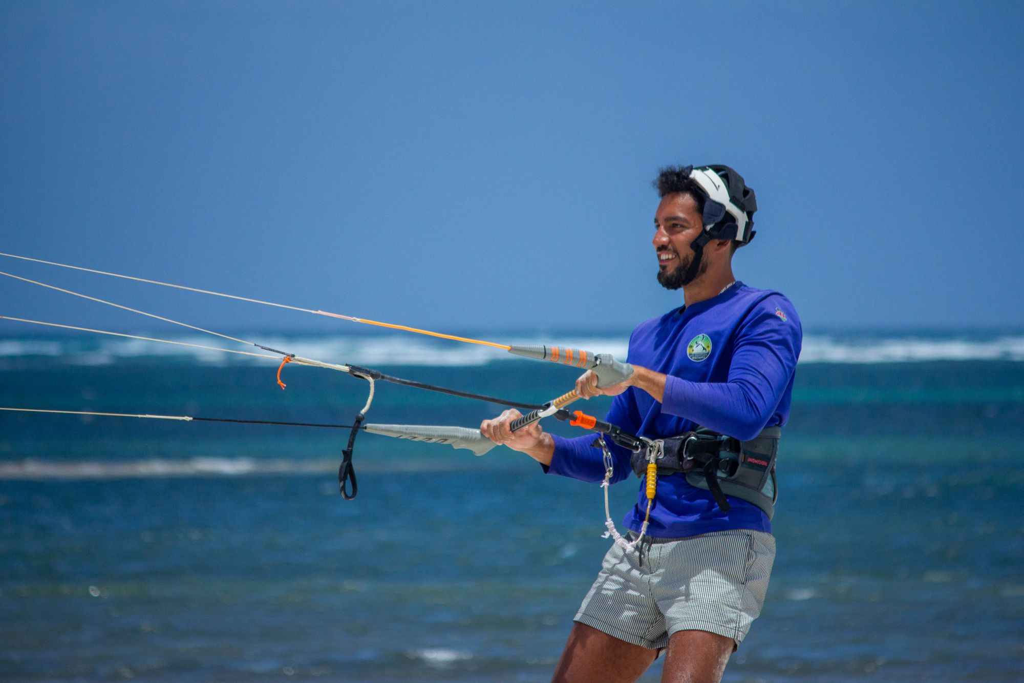Smiling student in a helmet holding the control bar with the kite lines stretched out