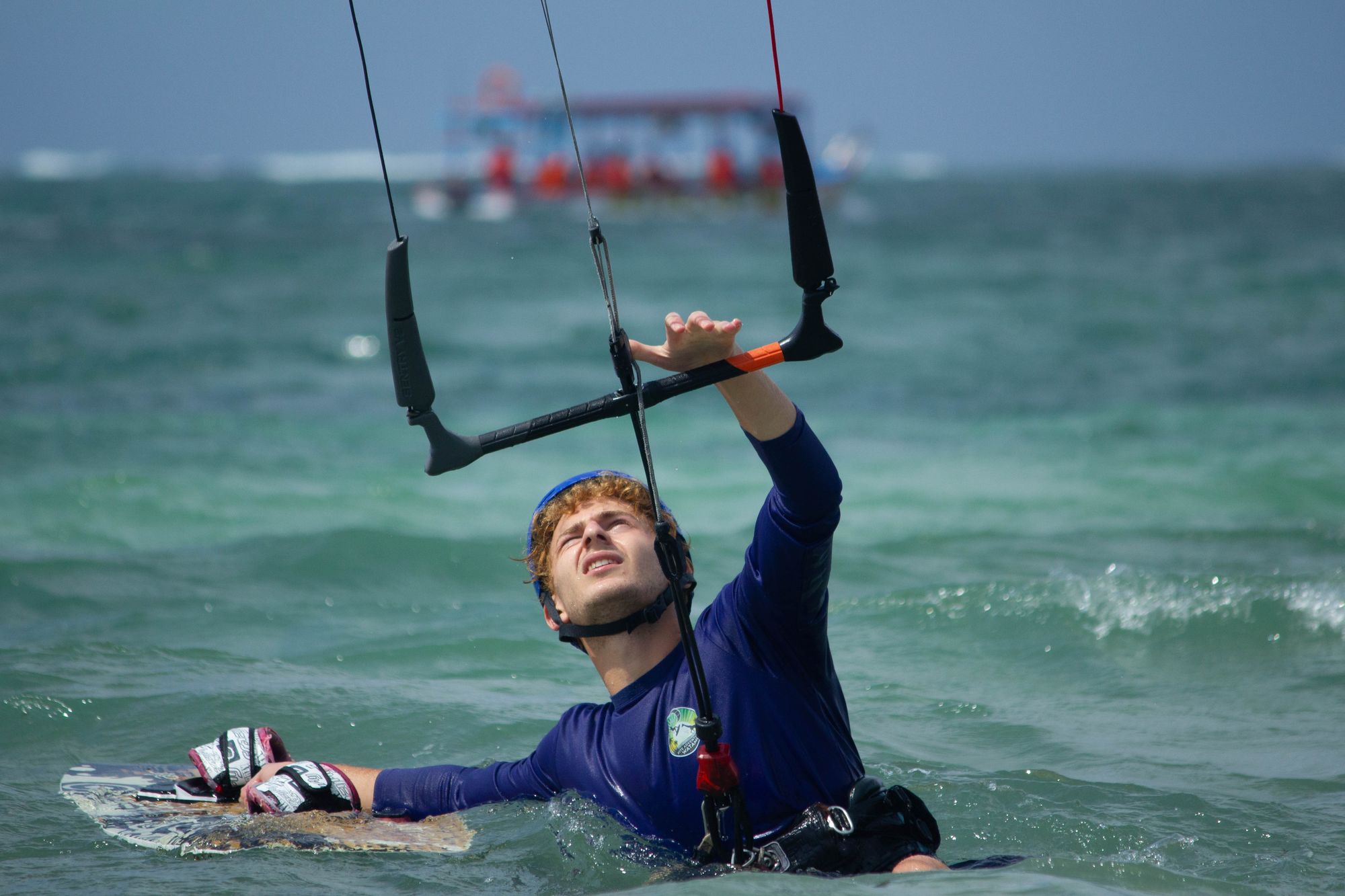 Student lying in the water with the board, looking up at the kite before a water start
