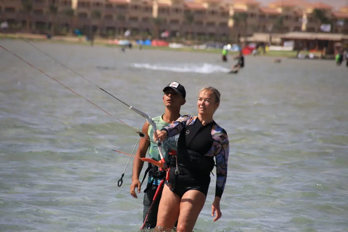 A kite instructor standing behind a student in the Safaga lagoon while she holds the kite bar