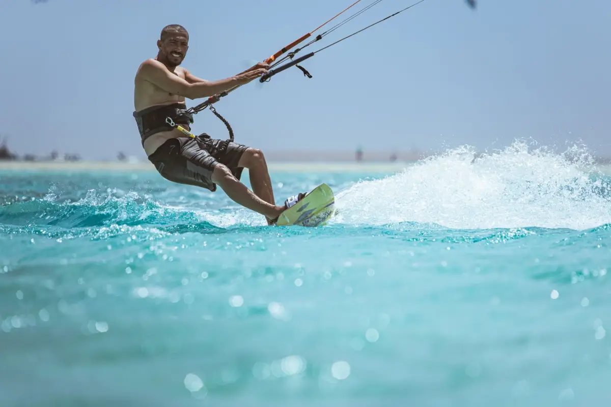 Kitesurfer carving a turn on a board in bright turquoise water