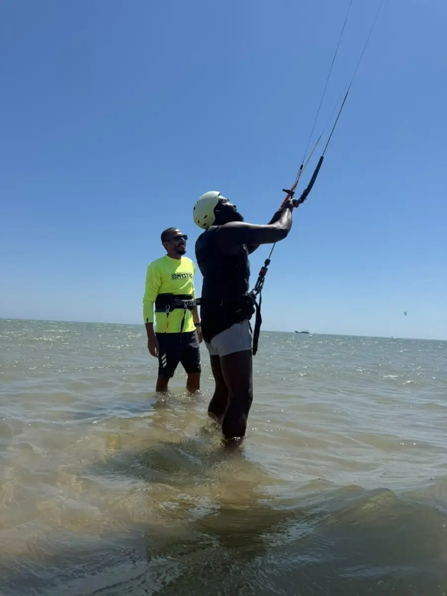 Instructor and student flying a kite together in shallow water