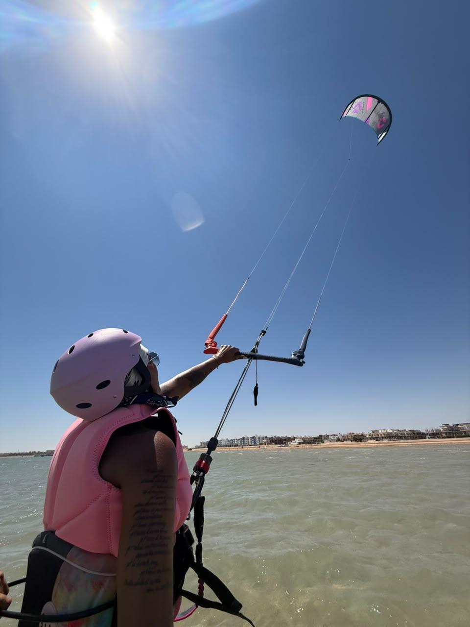 Student in a pink helmet and vest flying a kite during a lesson