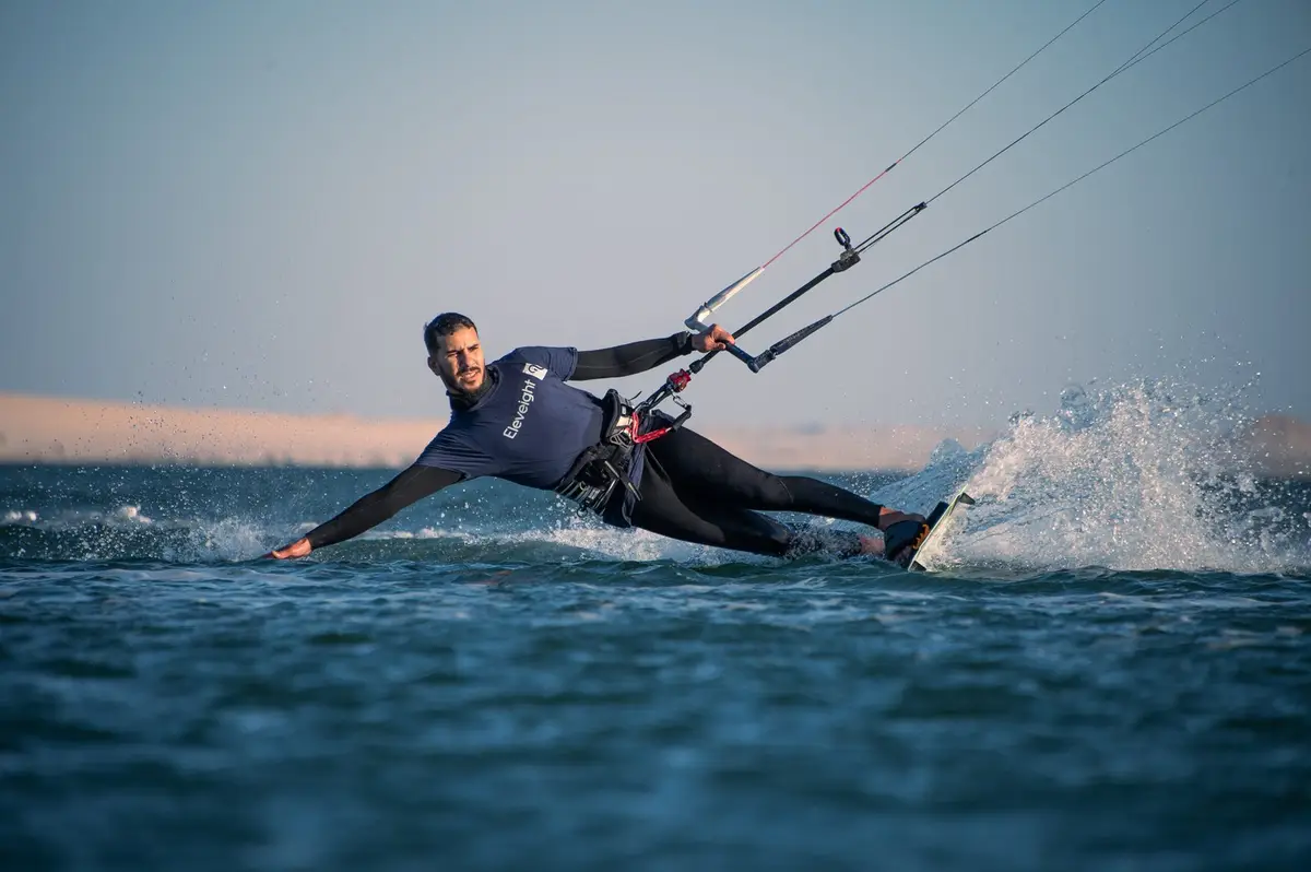A kitesurfer carving a turn on the Dakhla lagoon with spray flying
