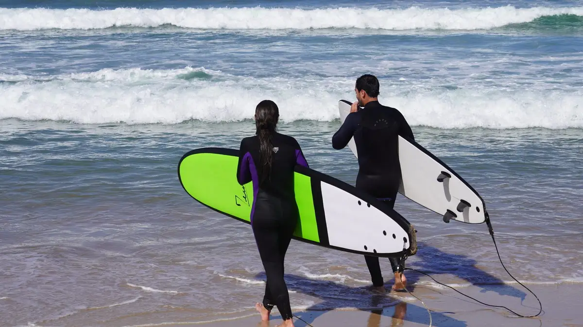 Two surfers carrying their boards into the sea near Dakhla
