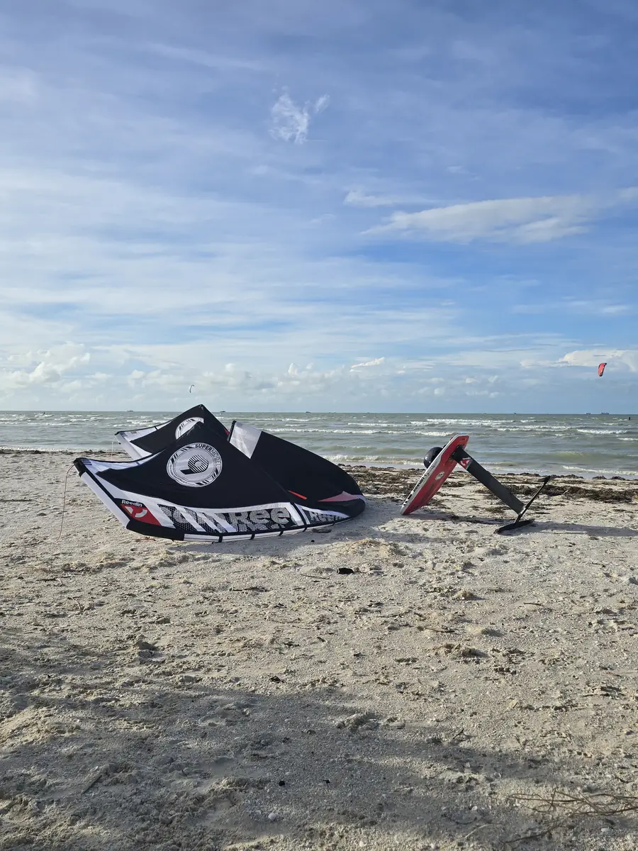 A black kite and a foil board lying on the beach at Progreso