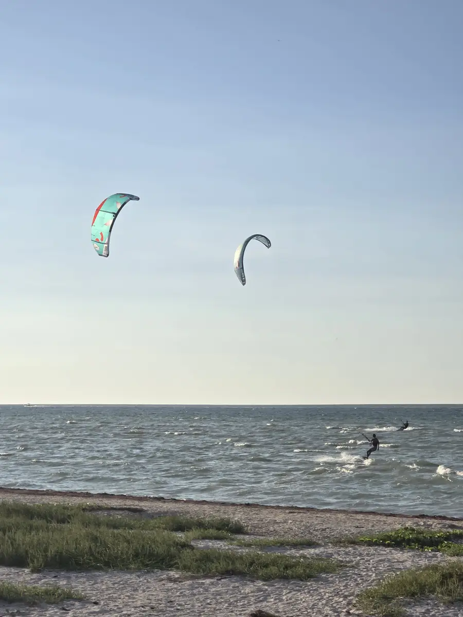 Two kites in the air over the bay, a rider on the water below