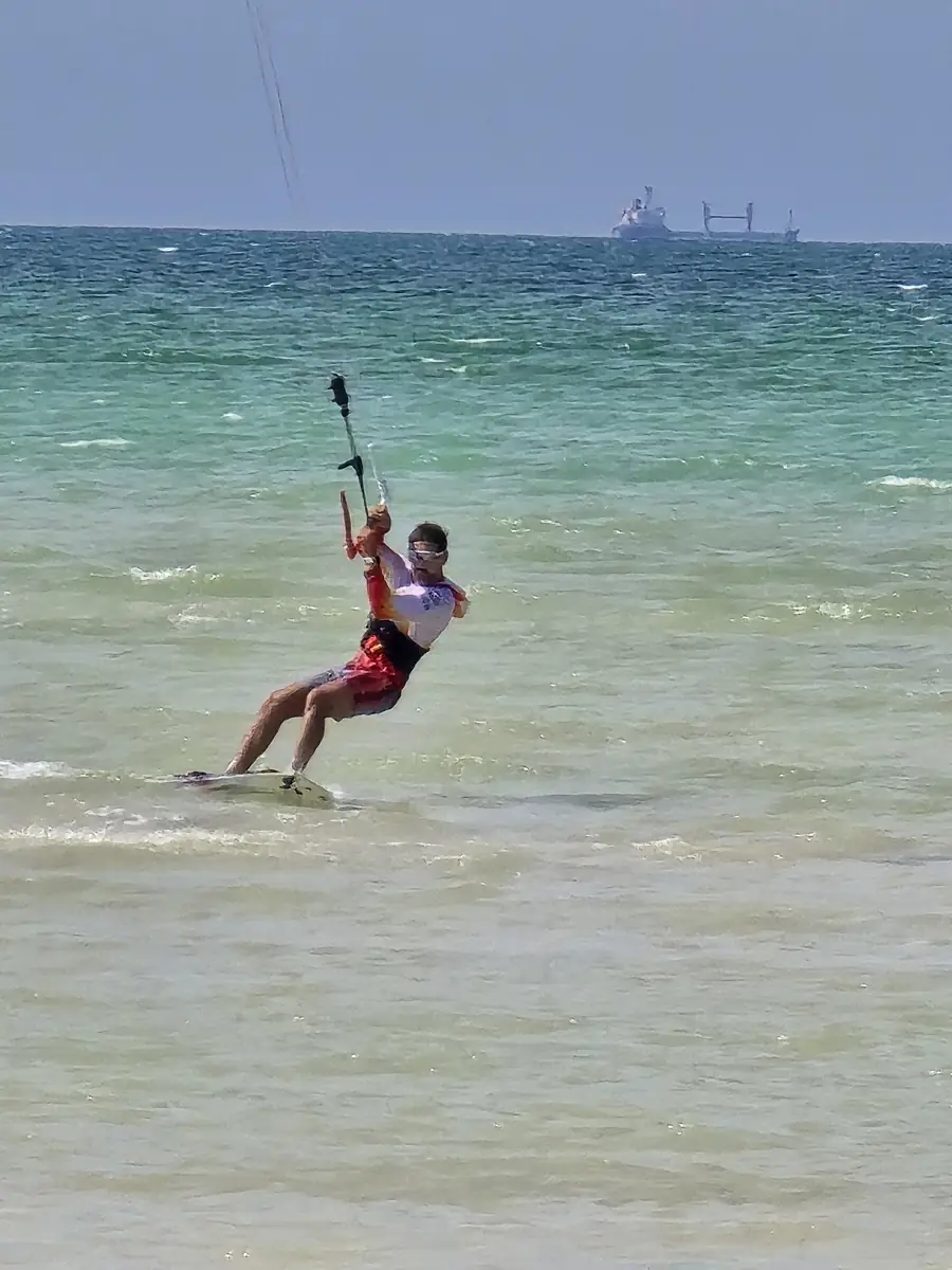 Rider on a kiteboard pulled by a kite over shallow turquoise water
