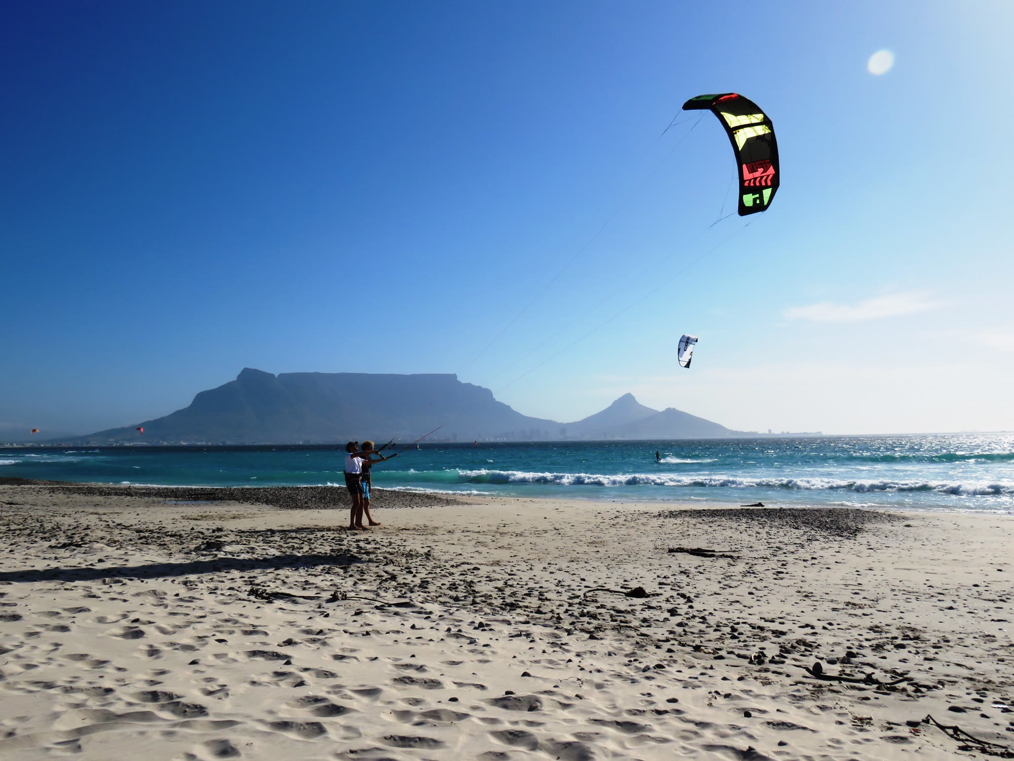 Kiter on the sand with the kite up and Table Mountain on the horizon