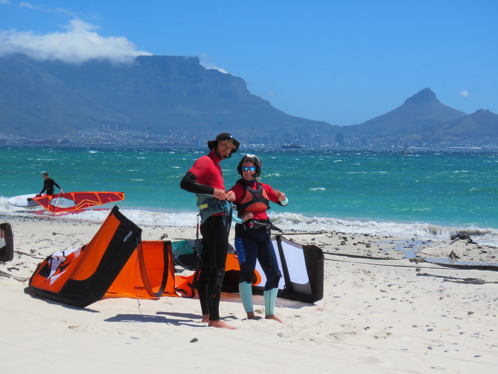 Instructor and student with an orange kite on the beach, Table Mountain behind