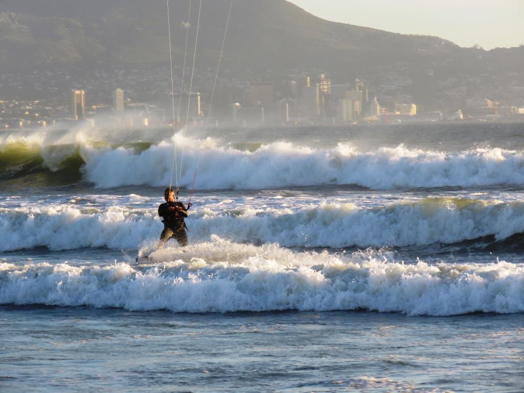Kitesurfer riding the waves with Cape Town's city and mountain behind