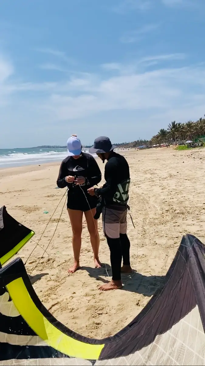An instructor and a student standing on the beach in Mui Ne with the kite lying on the sand in front of them