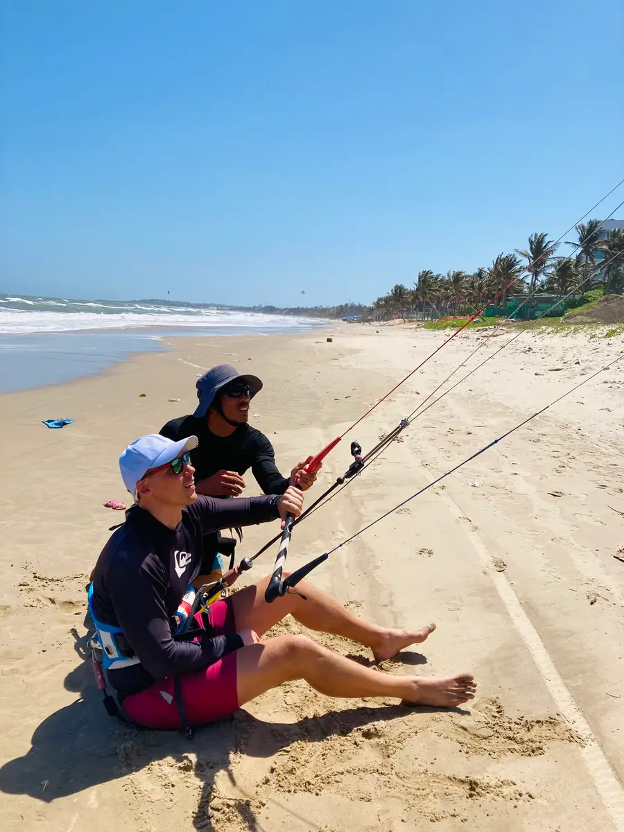 A kitesurf lesson on the beach in Mui Ne: instructor and student sit on the sand with the bar and lines