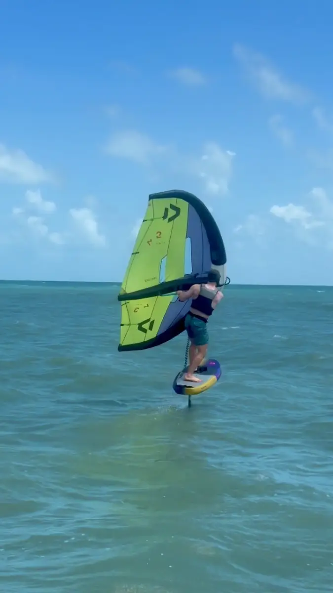 A rider flying a wing foil board over turquoise water at Cumbuco