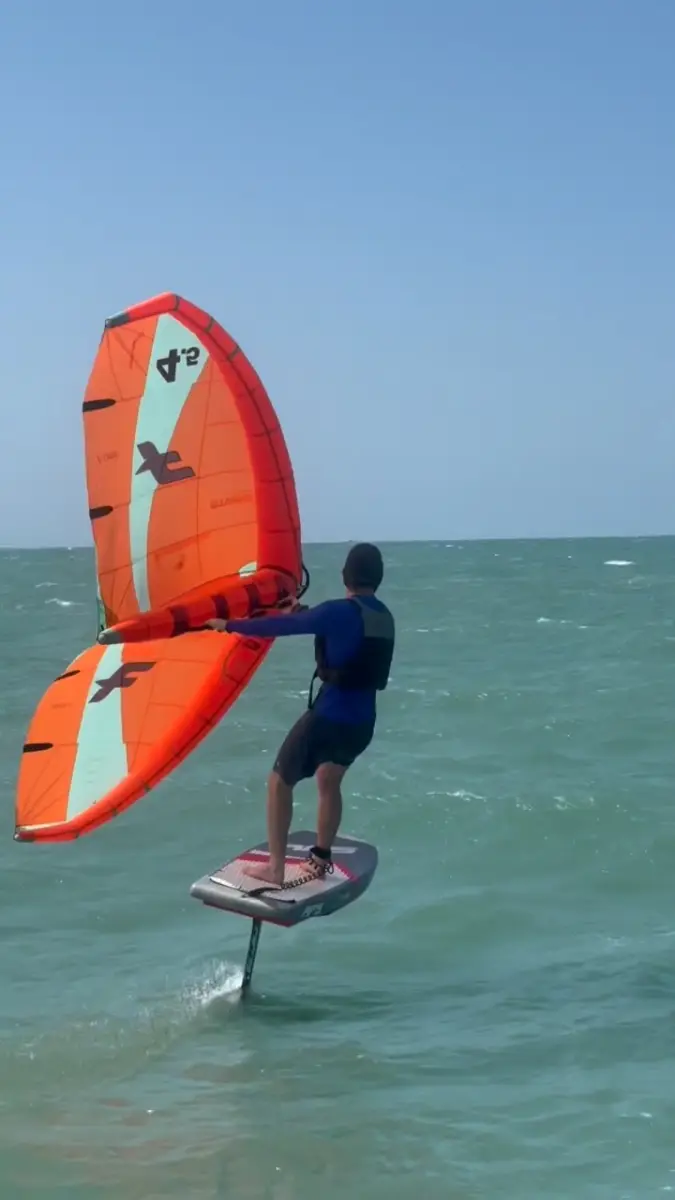 A rider foiling on the open sea at Cumbuco with an orange wing